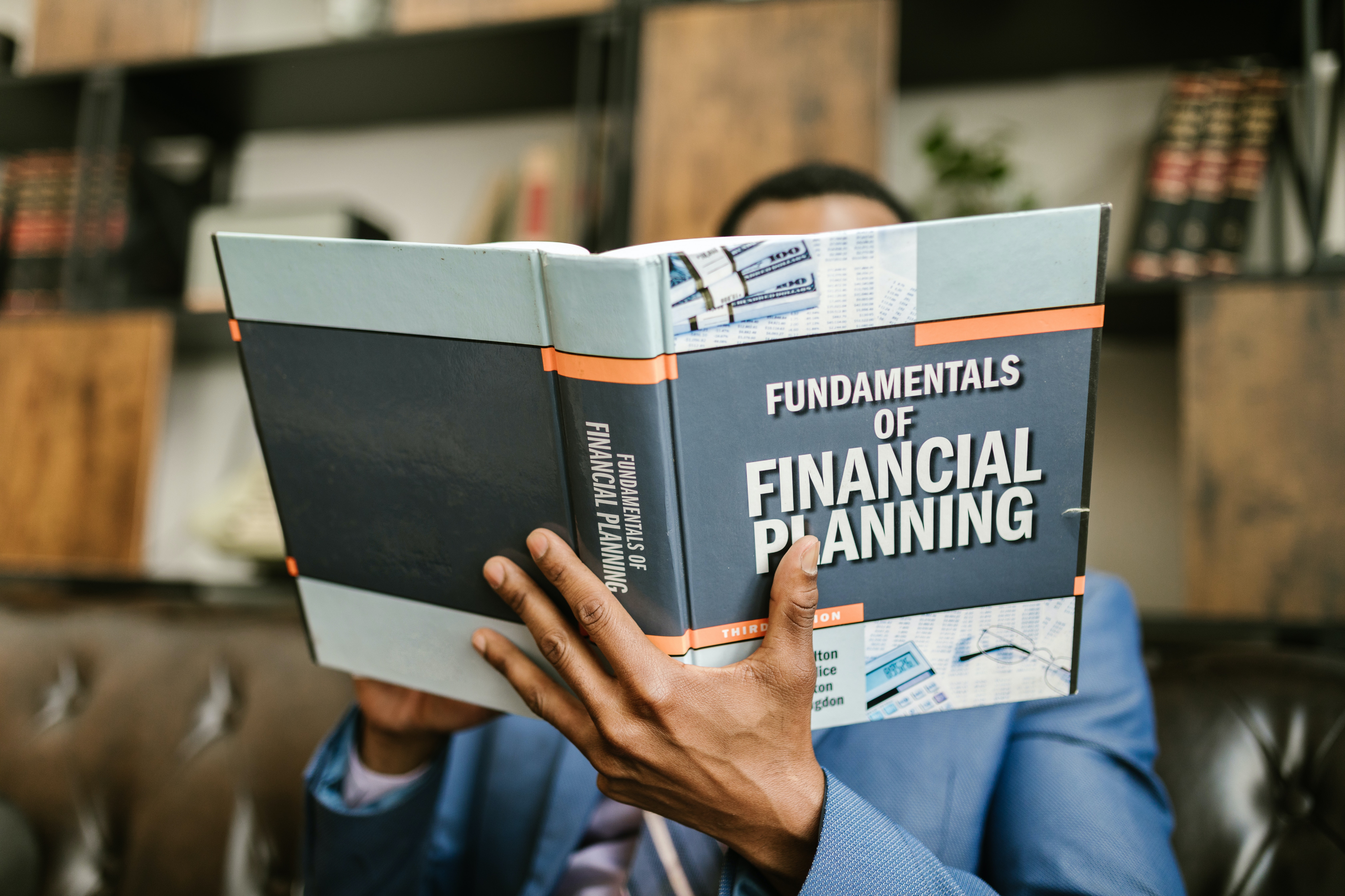 Person holding up book titled "Fundamentals of Financial Planning"